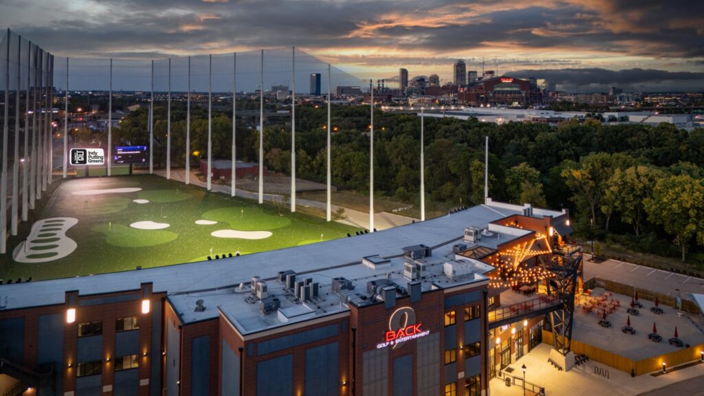 Back 9 golf entertainment venue in Indianapolis with synthetic turf driving range and putting greens at dusk